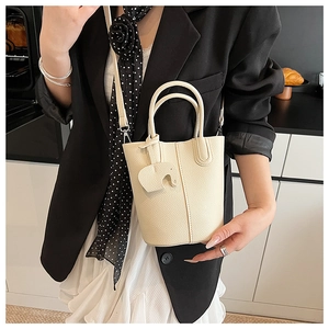 Detail of cream white litchi pattern bucket bag with cute elephant charm and thin strap