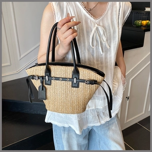 Detail of woven straw tote bag featuring black leather trim and silver eyelets accents