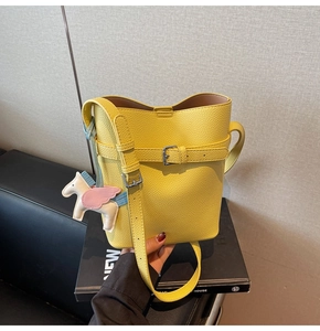 Close-up of yellow lychee pattern bucket bag with white pegasus charm and silver buckle