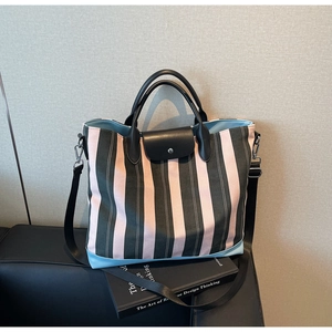 Detail of pink and green striped canvas tote bag with leather flap and snap closure