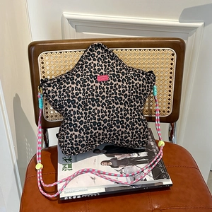 Star-shaped leopard print shoulder bag with colorful braided rope strap on a chair