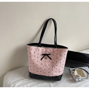 Dettaglio della borsa rosa con stampa a fiocco nero e ciondolo a cuore in metallo