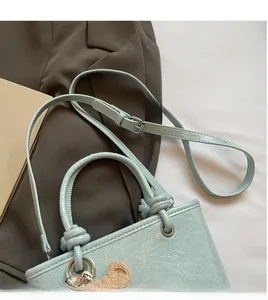 Light blue bucket bag with adjustable shoulder strap and a cute brown plush bear charm