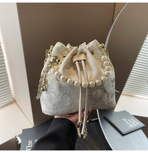 Detail of elegant bucket bag with white floral lace, pearl handle and 3D bow decoration