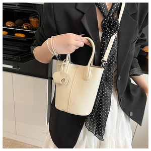 Close-up of cream-white bucket bag with lychee texture and cute elephant charm detail