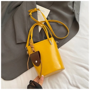 Detailed macro view of yellow bucket bag with lychee texture and brown pendant on a blazer