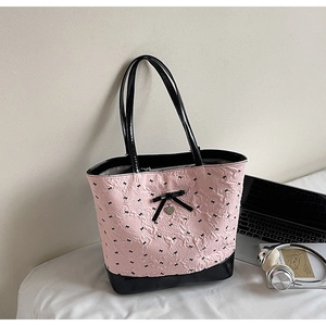 Borsa tote rosa con ricami di fiocchi neri e ciondolo a cuore in un ambiente moderno