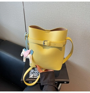 Detailed shot of yellow litchi grain bucket bag with a colorful pegasus pendant