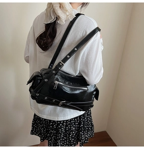 Detail of black Y2K pillow bag with silver zippers and metal eyelets on shoulder straps