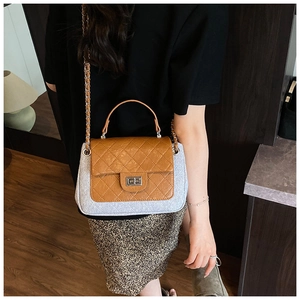 Detail of quilted stitching and metal turn-lock closure on two-tone crossbody bag
