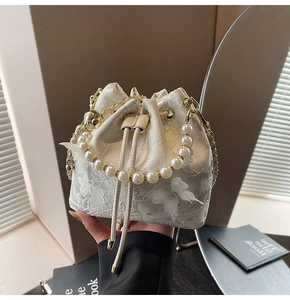 Detail of floral lace bucket bag with 3D butterfly accents and pearl handle strap