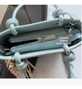 Detail view of the smooth silver zipper and lychee texture on the light blue tote bag
