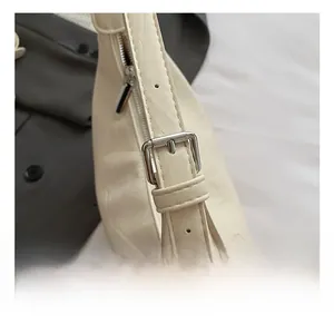 Gros plan sur les ferrures argentées et la bandoulière réglable du sac fourre-tout beige