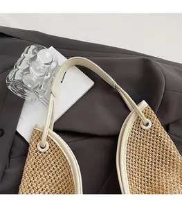 Close-up of straw woven tote with cream leather shoulder strap and neat edge stitching
