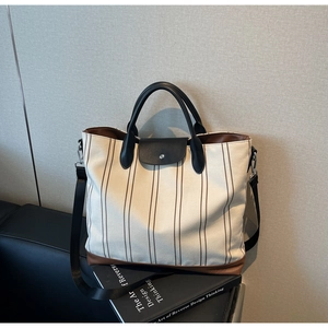 Detail of canvas tote bag with brown stripes, leather handles and detachable nylon strap