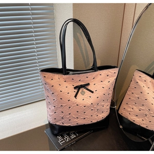 Dettaglio della borsa tote rosa con fiocchi neri e ciondolo a cuore in metallo argento