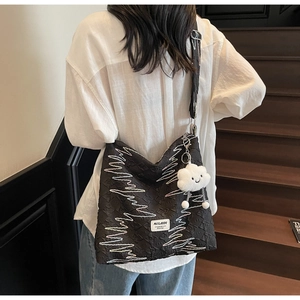 Detail of black drawstring tote bag with colorful wavy lines and cloud plush charm