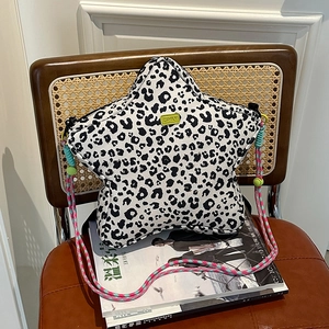 Star-shaped leopard print shoulder bag with colorful woven strap on a rattan chair