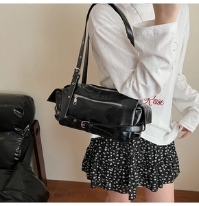 Side view of a black punk style pillow bag with multiple zippers and wide strap on model