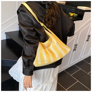 Détail du sac cabas en maille rayée jaune montrant la texture creuse et les bords en cuir
