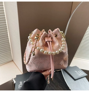Detail of pink bucket bag featuring lace embroidery, pearl handle, and 3D butterfly decor