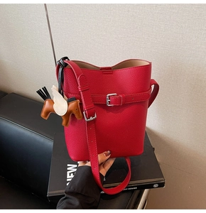 Detail of red lychee leather bucket bag featuring a tricolor leather horse charm
