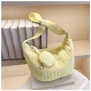 Detail of light yellow quilted crescent bag with adjustable strap and small round coin purse