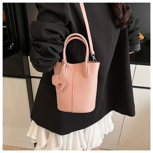 Pink lychee texture bucket bag with cute elephant charm shown on a chic outfit