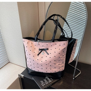 Dettaglio della borsa rosa con stampe di fiocchi neri e ciondolo a cuore in metallo