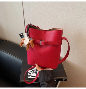 Detail of red lychee leather bucket bag with silver buckle and pony charm accessory