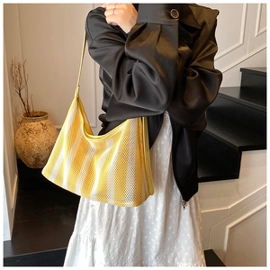Détail d'un sac cabas en maille rayée jaune et blanc avec bandoulière en cuir