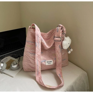 Detail of pink pleated canvas tote with rainbow stitching and white cloud charm