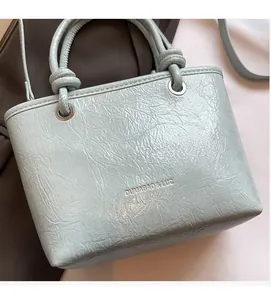 Detail showing mint green bucket bag with wrinkled texture and knotted top handles