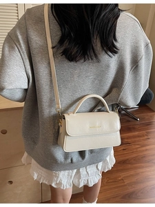 Creamy white rectangular leather handbag with handle and adjustable shoulder strap
