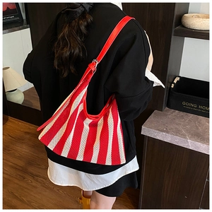 Détail du sac fourre-tout en maille rayée rouge et blanc avec bandoulière en cuir