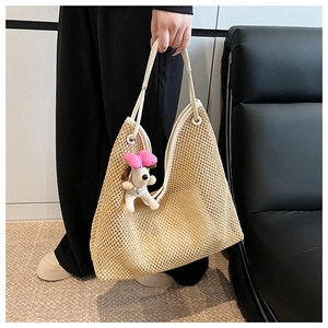 Detail view of woven straw tote bag with white leather handle and cute puppy charm