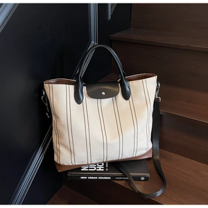 Detailed view of striped canvas tote with leather straps and detachable shoulder strap