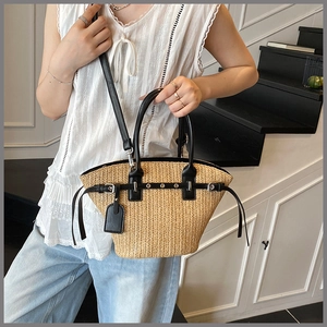 Detail of woven straw tote bag featuring black leather trim and metal eyelet accents