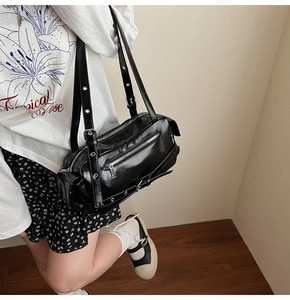 Detailed close-up of a black glossy PU leather shoulder bag with silver zippers and buckles