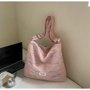 Detail of pink quilted hobo bag with colorful wave embroidery and adjustable strap