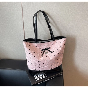 Dettaglio della borsa rosa con fiocchi, ciondolo a cuore e fondo in vernice lucida