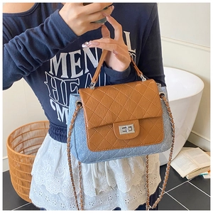 Detail of blue denim and brown quilted leather shoulder bag with a metal turn-lock closure