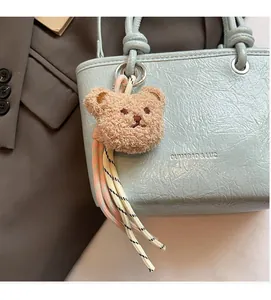 Detail of light blue wrinkled leather handbag with brown teddy bear charm and woven cord