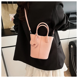 Pink lychee grain leather bucket bag with cute elephant charm shown in a lifestyle setting