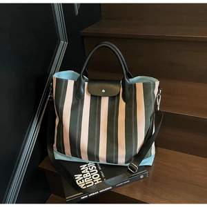 Close-up of a striped tote bag with green and pink stripes on wooden stairs