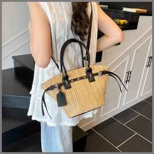 Detailed view of woven straw beach bag with black leather straps and shoulder strap