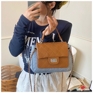 Detail of blue quilted tweed flap bag with brown leather trim and silver metal twist lock