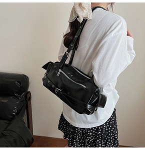 Detail view of black PU leather pillow bag with silver zippers and metal eyelet straps