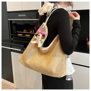 Detail of woven straw tote bag with mesh hollow design and cute puppy charm accessory