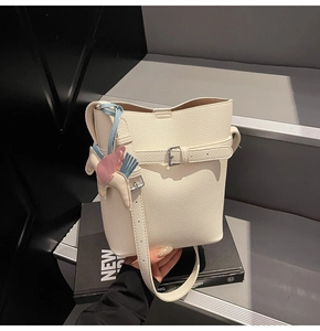 Close-up of cream lychee grain bucket bag featuring a decorative colorful horse charm